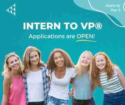 Girls smiling in front of the Intern to VP logo